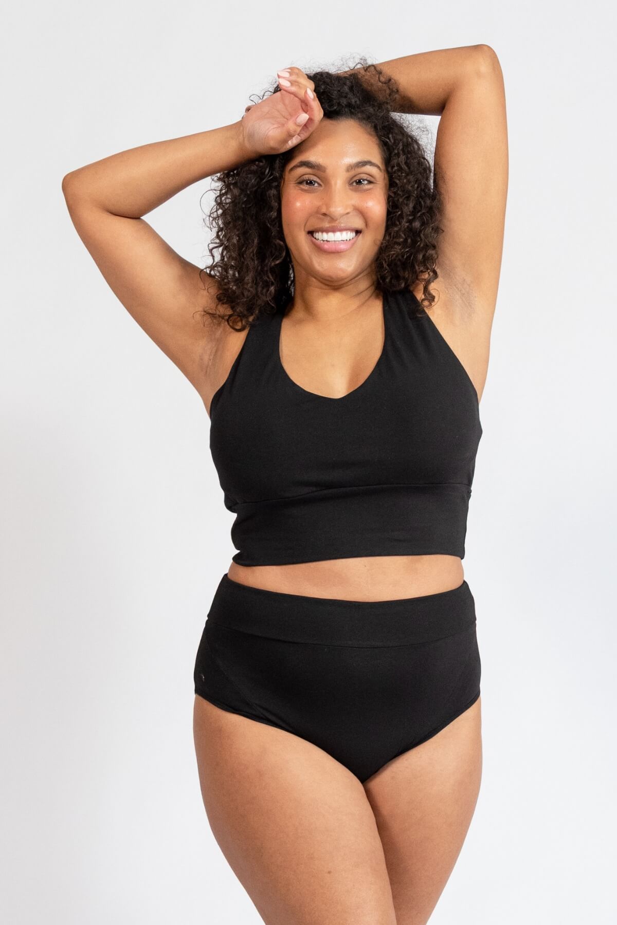 Woman wearing a black sports bra and high-waisted underwear on a white background