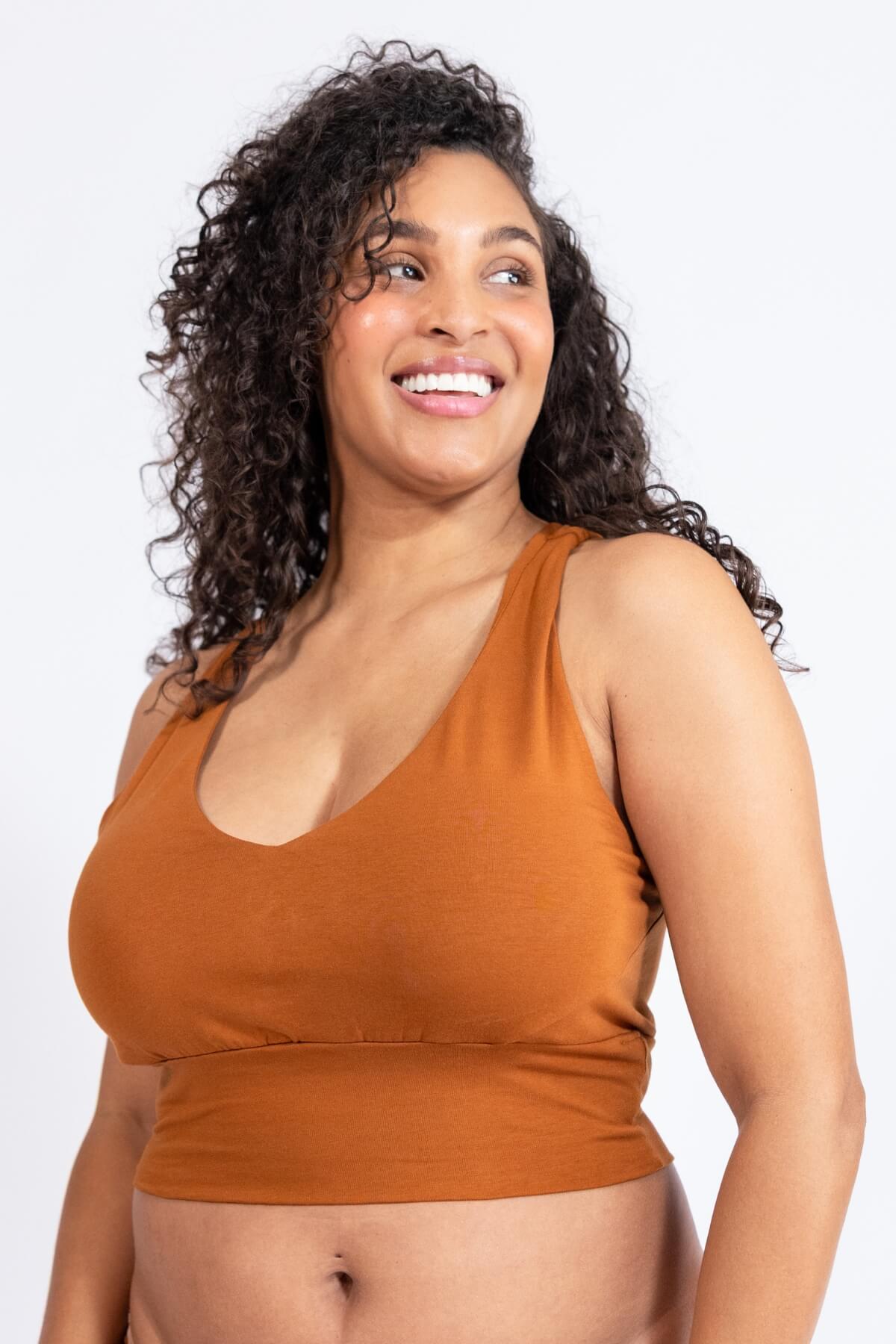 Woman wearing a caramel-colored tank top against a white background