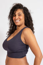 Woman wearing a dark blue sports bra against a white background