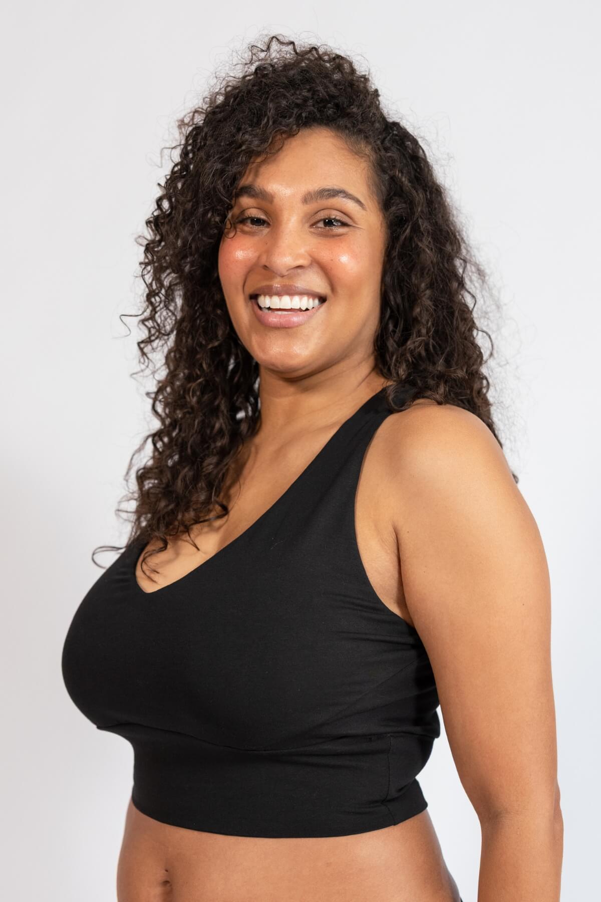 Woman wearing a black tank top against a plain background