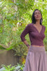 Woman wearing an organic cotton wrap top with wide leg turndown waist pants in a lush green jungle.
